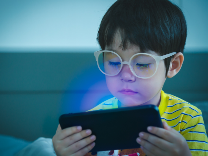 child with spectacles watching mobile weak eye vision