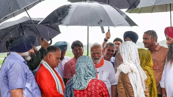 రైతులతో మోదీ ముచ్చట్లు.. వర్షంలో గొడుగు పట్టుకున్న ప్రధాని