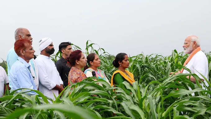 రైతులతో మోదీ ముచ్చట్లు.. వర్షంలో గొడుగు పట్టుకున్న ప్రధాని