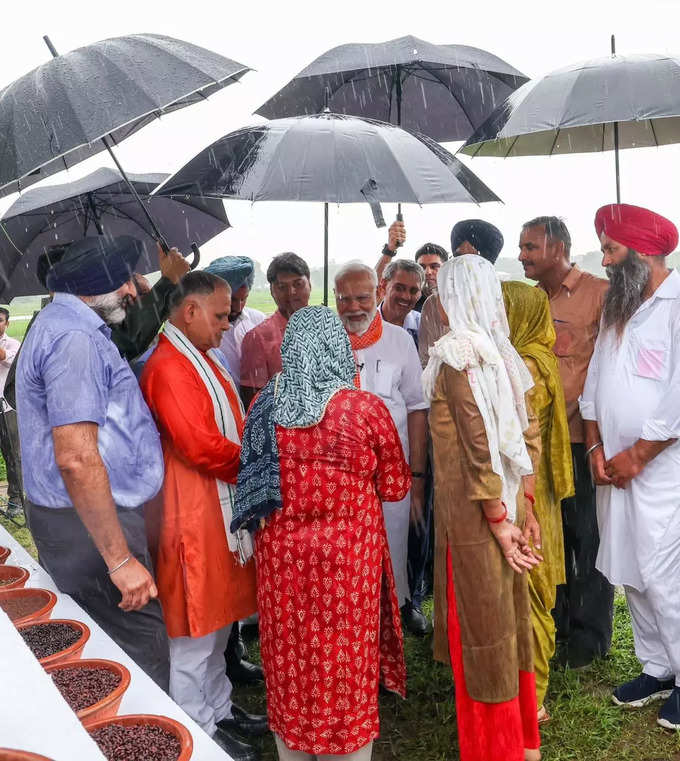 రైతులతో మోదీ ముచ్చట్లు.. వర్షంలో గొడుగు పట్టుకున్న ప్రధాని