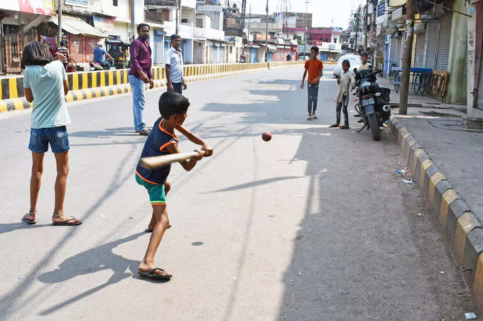 Children play cricket on a road