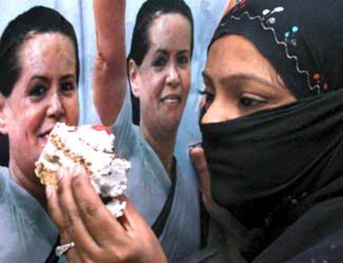 A Congress supporter offers sweets to a poster of party President Sonia Gandhi on the occasion of her 62nd birthday 