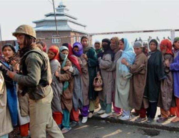 voters wait in queue outside a polling station to cast their vote in Srinagar