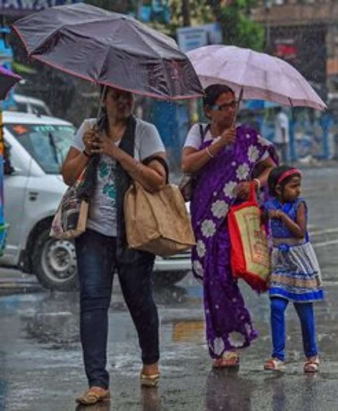 Kolkata: Pedestrians hold umbrellas to protect themselves from rain as they walk...