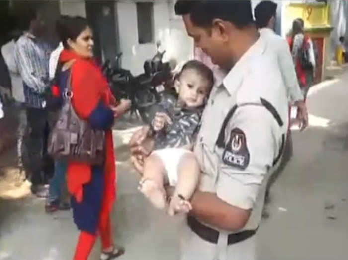 बच्चे का ध्यान रखते पुलिसकर्मी