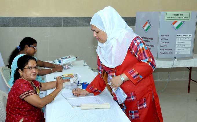 मुंबई में महाराष्ट्र विधानसभा चुनाव के दौरान वोट देने के लिए अपना नाम दर्ज करती एक वोटर।