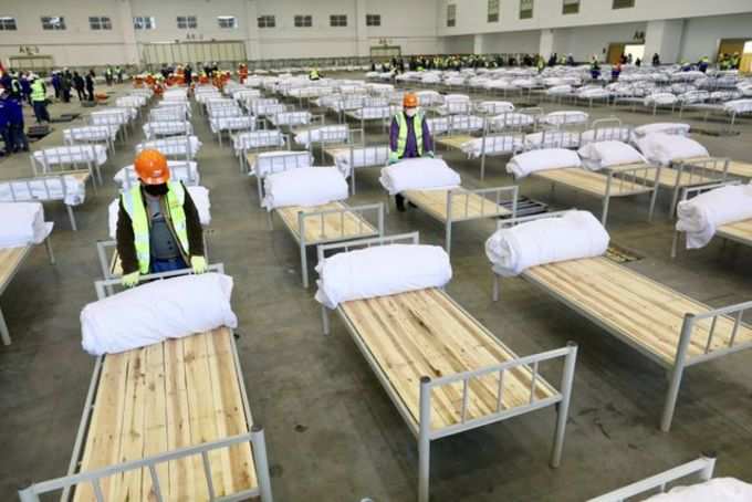 Workers set up beds at the Wuhan Parlor Convention Center to convert it into a makeshift hospital following an outbreak of the new coronavirus, in Wuhan