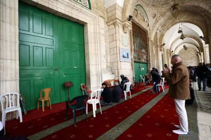 Muslim worshippers pray in front of the closed doors of Al-Aqsa mosque in Jerusalem&#39;s Old City