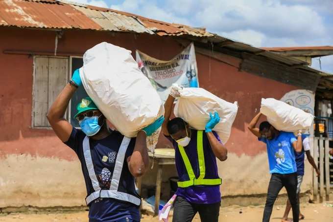 Volunteers carry sacks filled with food for vulnerable residents in Lagos, Nigeria, on April 9. (Temilade Adelaja/Reuters)