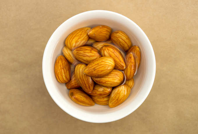 Raw almonds soaking in a white bowl of water