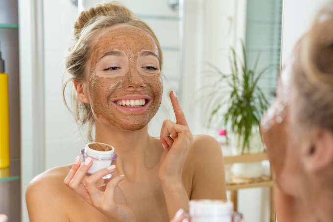 Young beautiful girl applying facial scrub mask