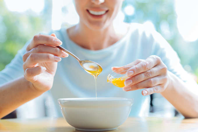 female adding honey to the porridge