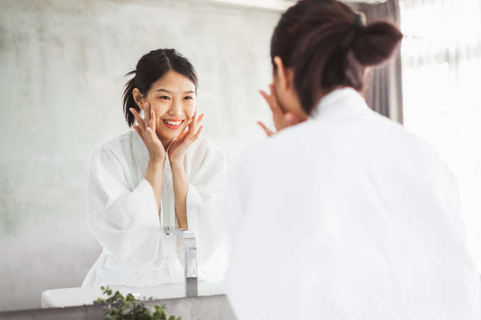 Asian woman cleaning face front of mirror