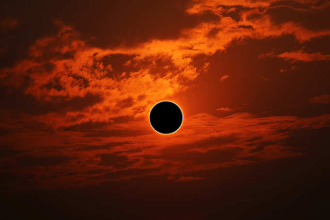 sun eclipse over silhouette orange cloud