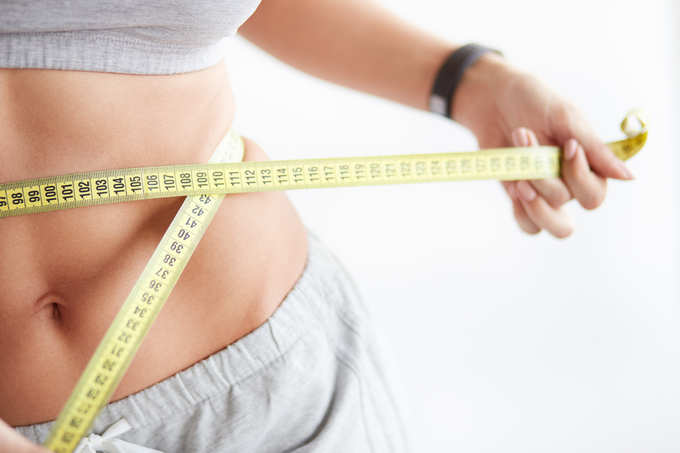 Slim young woman measuring her thin waist with a tape