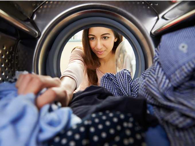 woman-doing-laundry-reaching-inside-washing-machine-picture-id469224234