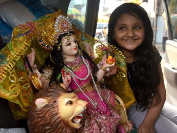 मां दुर्गा की छोटी प्रतिमा के साथ बच्ची
