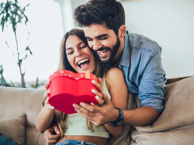 happy-couple-with-gift-box-hugging-at-home-picture-id1184893073