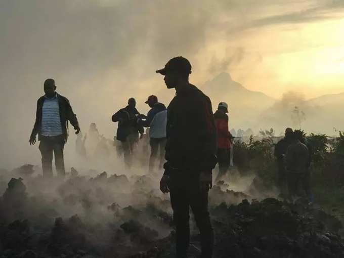 Residents walk near destroyed homes with the smouldering lava deposited by the eruption of Mount Nyiragongo volcano near Goma.