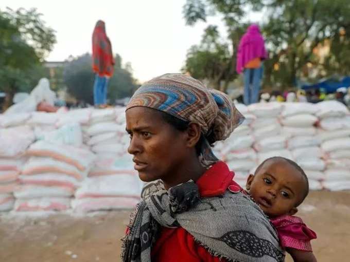 FILE PHOTO_ Woman carries an infant as she queues in line for food, at the Tsehaye primary school, in Shire.
