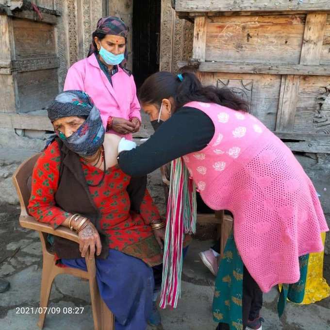 उत्तराखंडः उत्तरकाशी के सुदूर इलाके में एक महिला को कोरोना की वैक्सीन लगाती स्वास्थ्यकर्मी