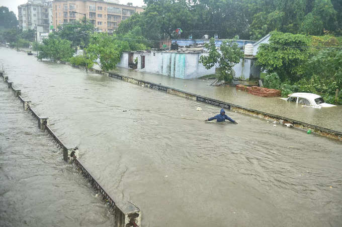 Lucknow: A man wades through a waterlogged area following heavy rains in Lucknow...