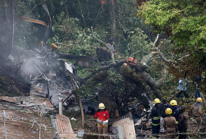 Rescuers stand near the debris of the Russian-made Mi-17V5 helicopter after it crashed near the town of Coonoor