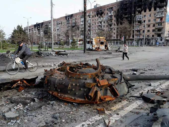 People walk near a destroyed tank in Mariupol (1).