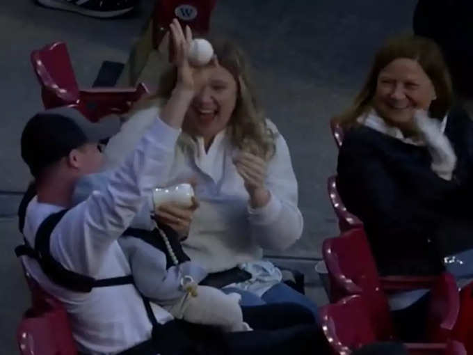 man catches baseball while baby on his lap