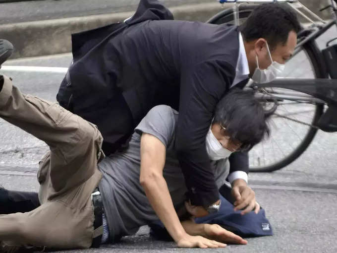 Tetsuya Yamagami, bottom, is detained near the site of gunshots in Nara Prefectu....