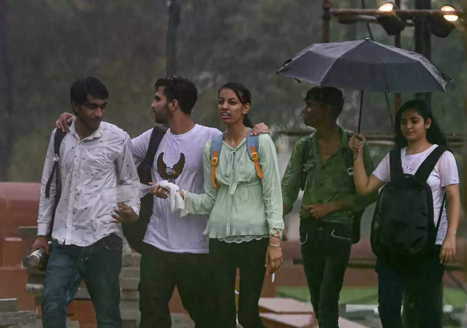 New Delhi_ Youngsters walks along a road near the India Gate amid monsoon rains,....