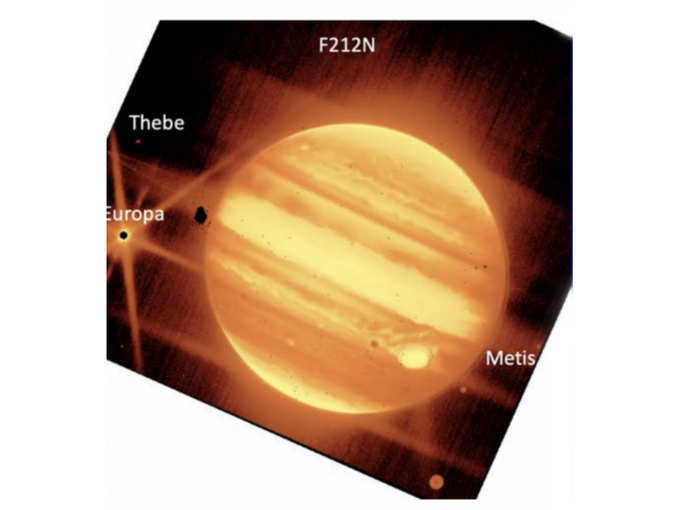 Jupiter, center, and its moons Europa, Thebe, and Metis are seen through the James Webb Space Telescope’s NIRCam instrument 2.12 micron filter.