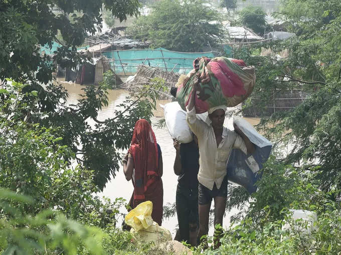 पानी बढ़ता देख बोरिया बिस्तर बांध सुरक्षित स्थान पर जाते लोगों की तस्वीर