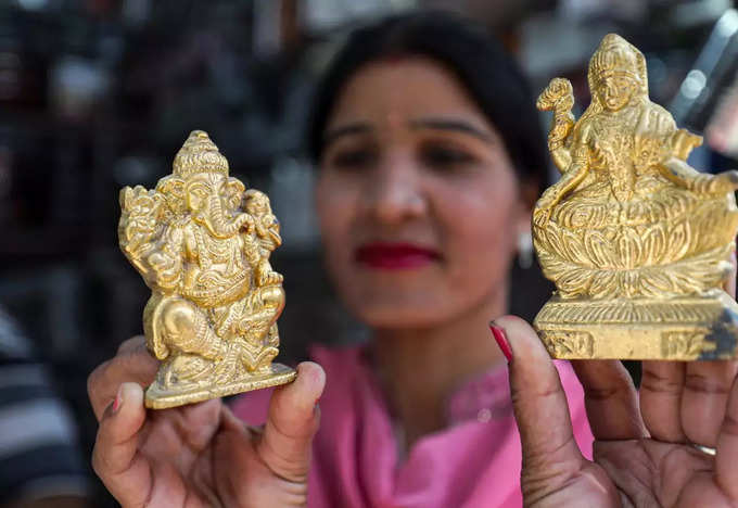 जम्मू में दिवाली से पहले गणेश-लक्ष्मी की आकर्षक मूर्ति को दिखाती एक महिला