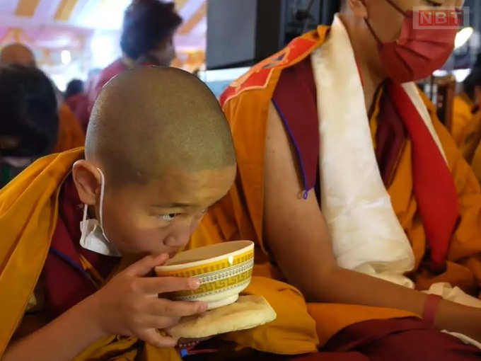 चाय और ब्रेड का आनंद लेता बाल बौद्ध भिक्षु