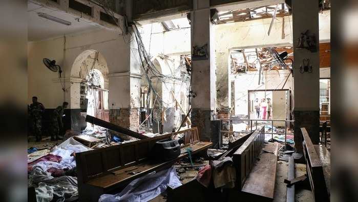 EDITORS NOTE: Graphic content / Sri Lankan security personnel walk past dead bodies covered with blankets amid blast debris at St. Anthony's Shrine following an explosion in the church in Kochchikade in Colombo on April 21, 2019. - A string of blasts ripped through high-end hotels and churches holding Easter services in Sri Lanka on April 21, killing at least 156 people, including 35 foreigners. (Photo by ISHARA S.  KODIKARA / AFP)