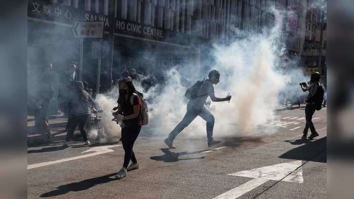 Protesters react after police fired tear gas to disperse them in the Sai Wan Ho district in Hong Kong on November 11, 2019. - A police officer shot a masked protester in an incident shown live on Facebook and a man was set on fire on November 11 during one of the most violent days of clashes in Hong Kong since pro-democracy unrest erupted more than five months ago. (Photo by DALE DE LA REY / AFP)