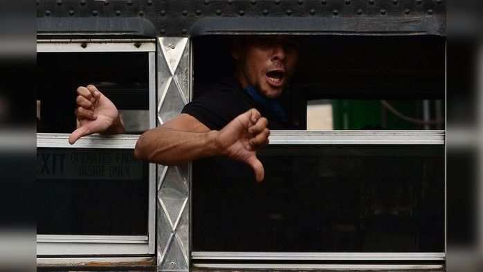 Honduran migrants, part of a group of 136 people deported from Mexico, shout and gesture aboard a bus upon their arrival at the Toncontin International Airport, in Tegucigalpa, on April 25, 2020 on their way to be placed under quarentine amid the Covid-19 pandemic. (Photo by ORLANDO SIERRA / AFP)