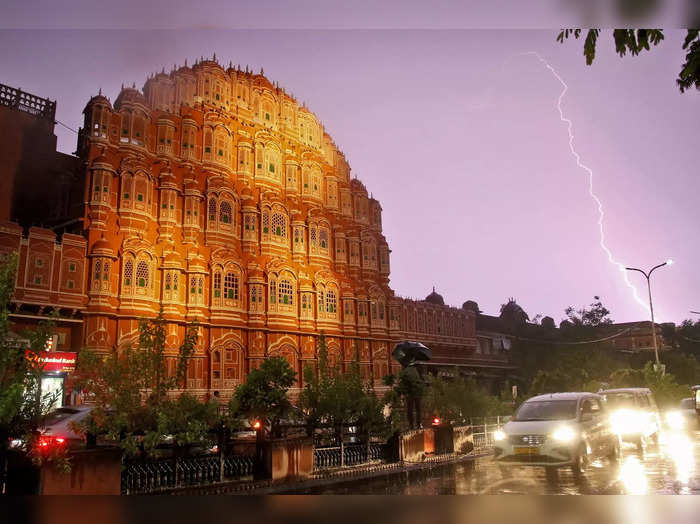 Jaipur: Vehicles ply near the Hawa Mahal during a lightning strike in the sky, i...