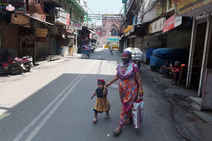 New Delhi: A woman walks with her kid during COVID-induced lockdown on a deserte...