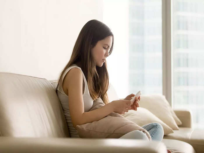 sad-teen-girl-using-phone-while-sitting-sofa