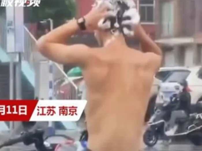चीन: ट्रैफिक सिग्नल पर बाइकर ने लगाया शैंपू, फिर बारिश के पानी से धो लिए बाल