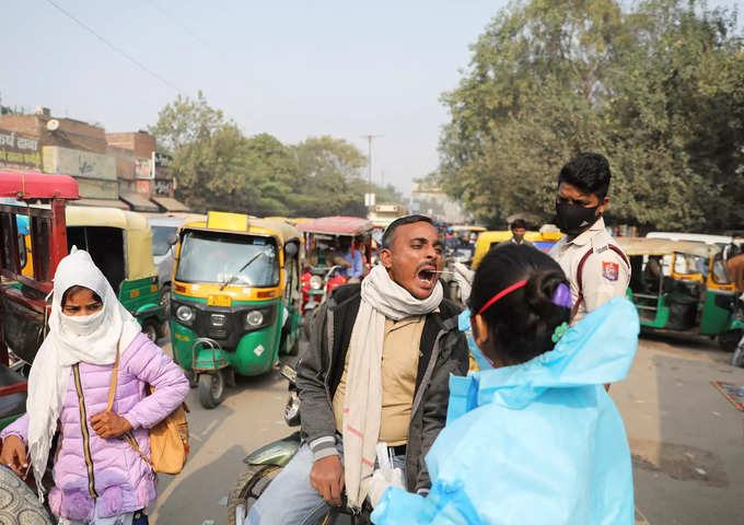 A healthcare worker collects a coronavirus disease (COVID-19) test swab sample from a man on a road in New Delhi