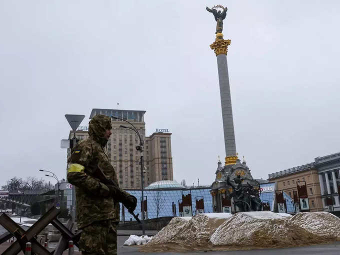 A soldier stands guard in front of bars and sand barriers at the Independence Square in Kyiv.