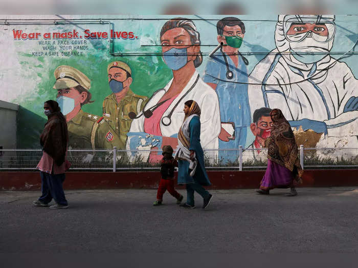Women walk past a graffiti amidst the spread of the coronavirus disease (COVID-19) in New Delhi