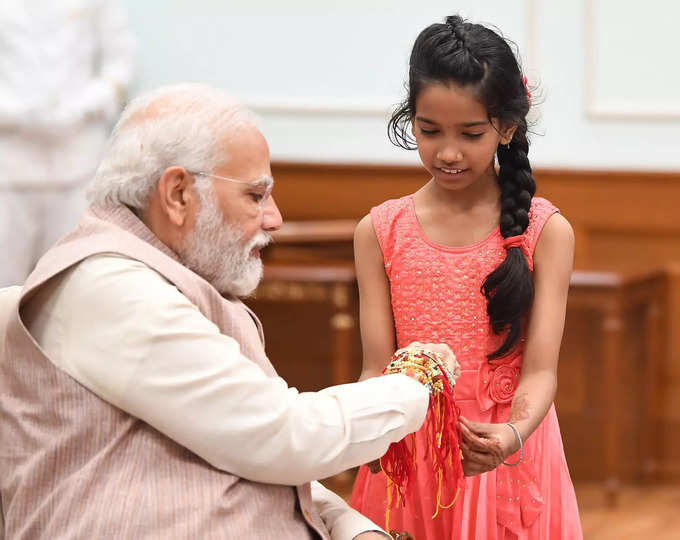 छोटी बच्ची से अपनी कलाई पर राखी बंधवाते पीएम नरेंद्र मोदी