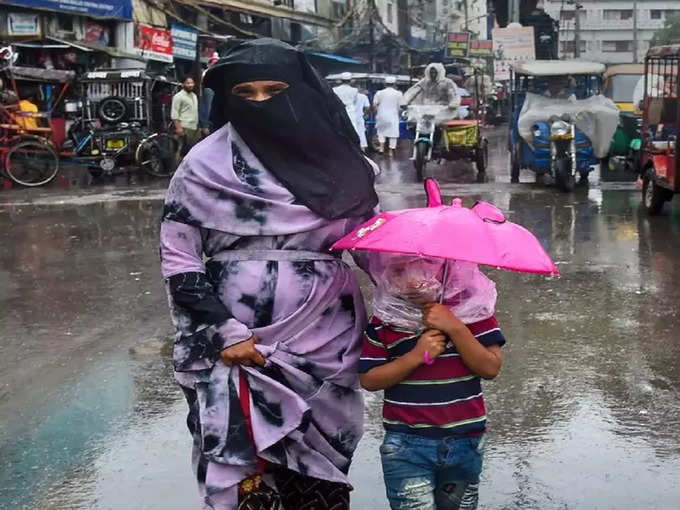 अपने बच्चे को छाता और मुंह पर पॉलीथीन लगाकर बारिश से बचाने की कोशिश करती यह महिला